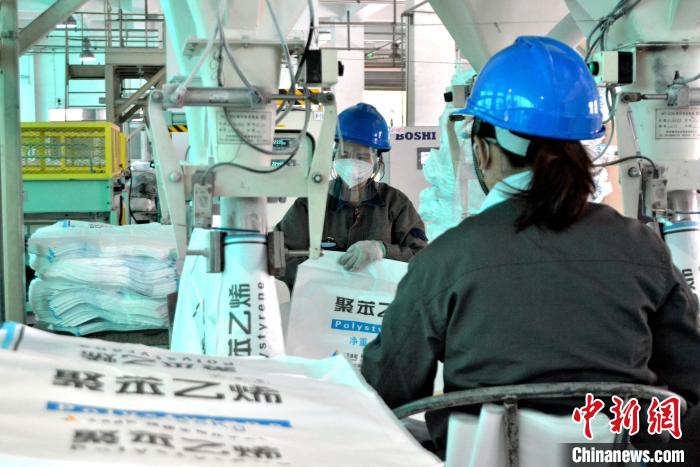 工人在生產(chǎn)線上包裝聚苯乙烯產(chǎn)品?！×趾霔v 攝