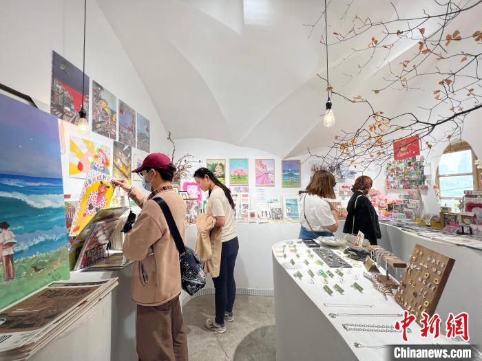 圖為藝術(shù)品商店內(nèi)，顧客挑選插畫(huà)作品?！＄婌?攝