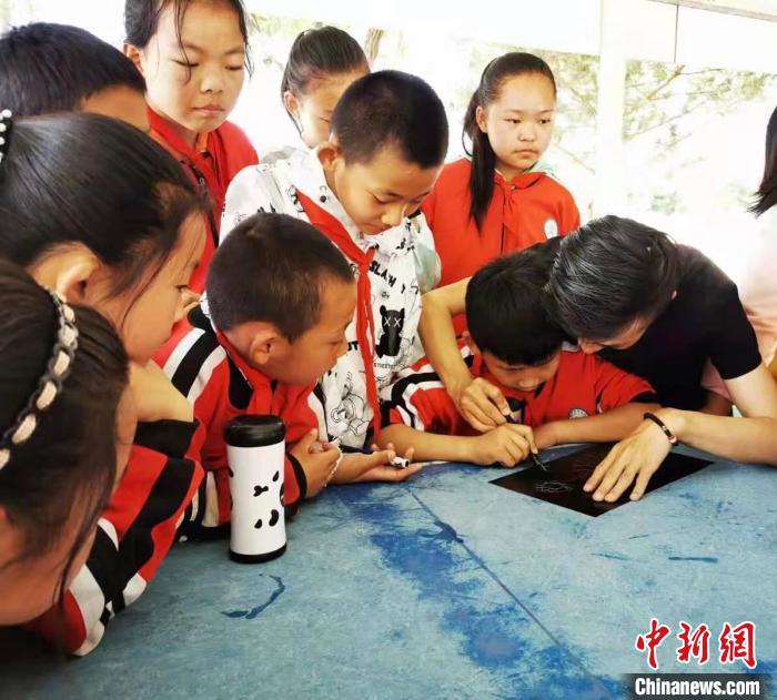 圖為朱增平(右一)教學(xué)生創(chuàng)作鍥金畫。(資料圖) 受訪者供圖