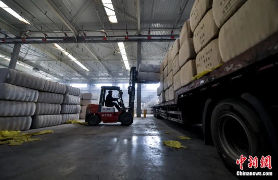 新疆喀什綜合保稅區(qū)，喀什啟路國際貿(mào)易有限公司的倉庫內(nèi)，工人正在裝載從塔吉克斯坦和烏茲別克斯坦進口的棉花。劉新攝
