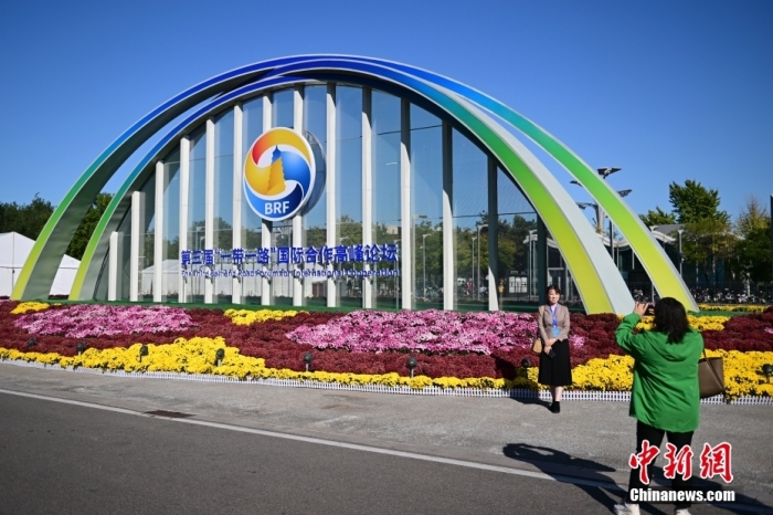 10月15日，北京，工作人員在國家會議中心外的第三屆“一帶一路”國際合作高峰論壇景觀布置前拍照留念。當(dāng)日，位于國家會議中心的第三屆“一帶一路”國際合作高峰論壇新聞中心啟動(dòng)試運(yùn)行。據(jù)悉，第三屆“一帶一路”國際合作高峰論壇將于10月17日至18日在北京舉行。<a target='_blank' href='/'><p  align=