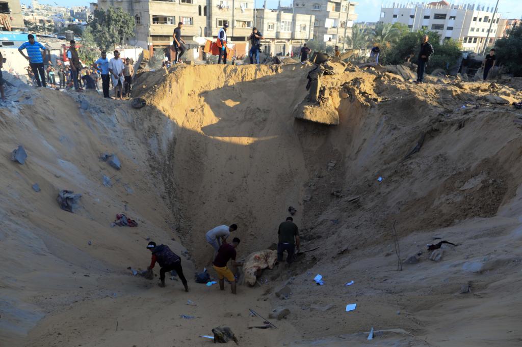 10月16日，在加沙地帶南部城市汗尤尼斯，人們在遭以色列襲擊后的建筑廢墟中救援傷者。 新華社發(fā)（亞西爾·庫迪 攝）
