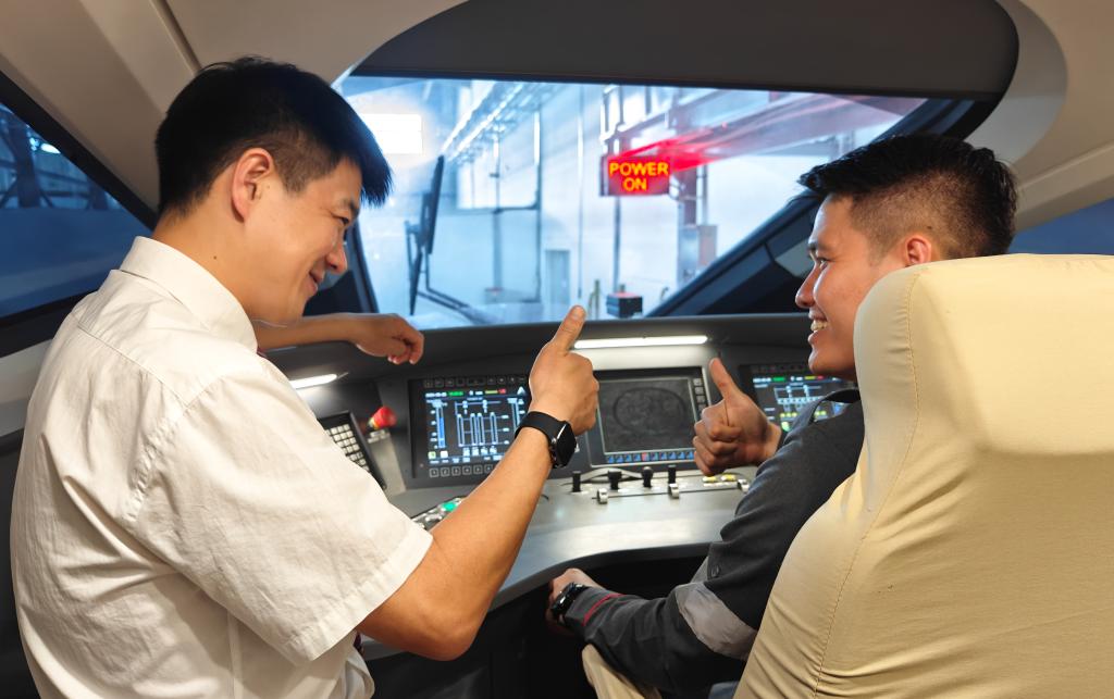 8月25日，在印度尼西亞萬隆的雅萬高鐵德卡魯爾動車所內(nèi)，中國師傅穆振（左）在向印尼火車司機(jī)塞蒂亞萬講解動車組出庫前的上電作業(yè)。