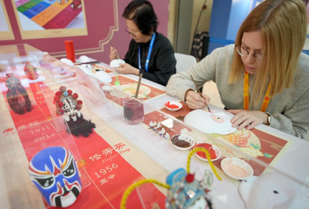 10月16日，在第三屆“一帶一路”國際合作高峰論壇新聞中心，來自比利時的記者（右）體驗畫京劇臉譜。新華社記者 王毓國 攝