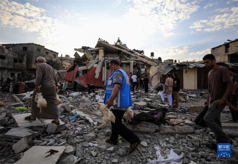 10月27日，在加沙地帶南部城市汗尤尼斯，人們經(jīng)過以軍襲擊后的房屋廢墟。