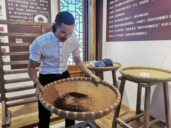 2023“一帶一路”媒體合作論壇聯(lián)合采訪團團員在非遺文化展示館體驗中藥炮制技藝。（本報記者 黃超攝）