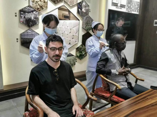 2023“一帶一路”媒體合作論壇聯(lián)合采訪團團員在九牛草展示館體驗艾灸。（本報記者 黃超攝）