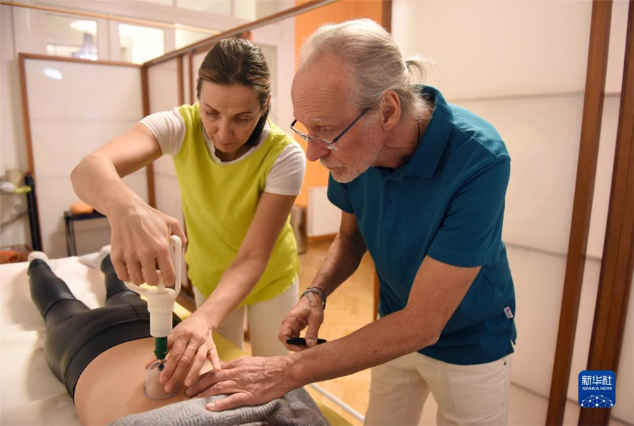 12月12日，在奧地利維也納，科格勒醫(yī)生（右）和助手在為病人進(jìn)行拔罐治療。新華社記者 賀燦鈴 攝