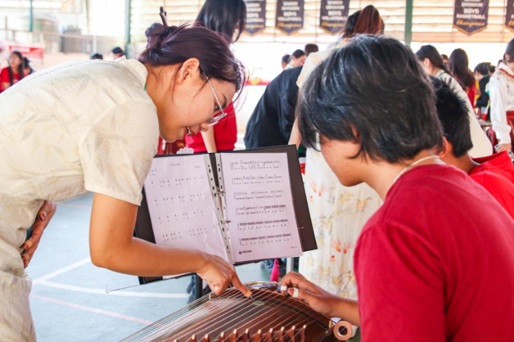 志愿者教師指導(dǎo)學(xué)生彈奏古箏。活動(dòng)主辦方供圖