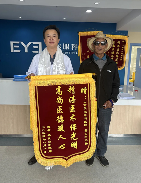 達(dá)瓦老人向吳四華（左）贈(zèng)送錦旗。受訪(fǎng)者供圖