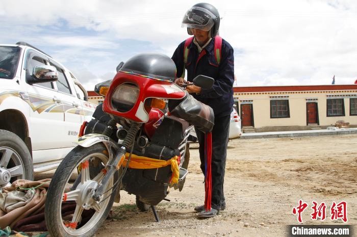 圖為白瑪準(zhǔn)備騎摩托車(chē)巡湖?！≮w朗 攝