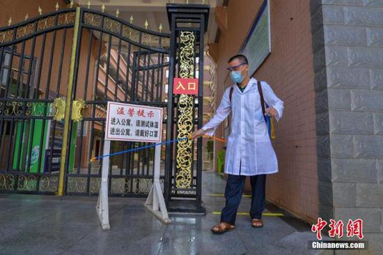 資料圖：?？诮?jīng)濟(jì)學(xué)院的工作人員在學(xué)生宿舍樓入口消毒。 中新社記者 駱云飛 攝