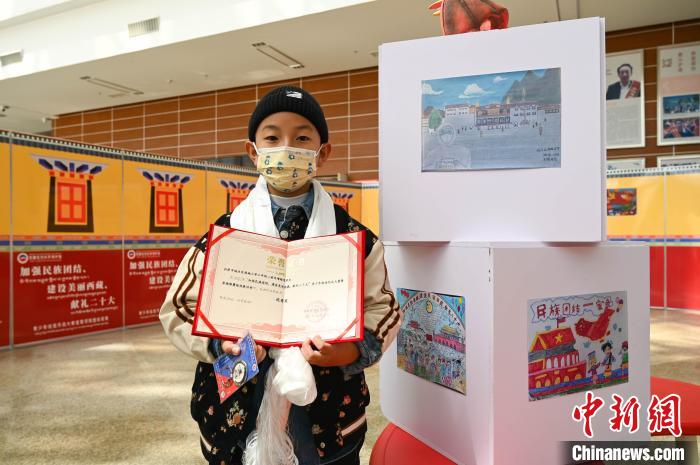 圖為一名獲獎學(xué)生與自己的繪畫作品合影。　趙朗 攝