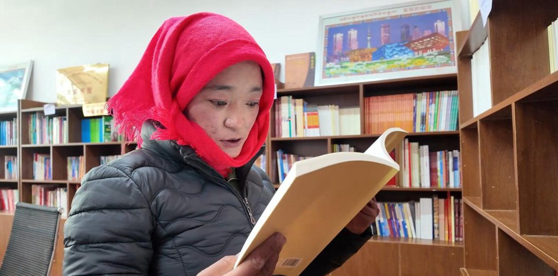 一名婦女正在認(rèn)真閱讀書籍。申扎縣融媒體中心供圖