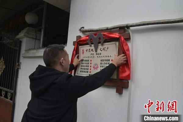 桂溪鎮(zhèn)渭溝村政府工作人員為“十星級(jí)文明戶(hù)”掛上牌匾。　楊勇 攝