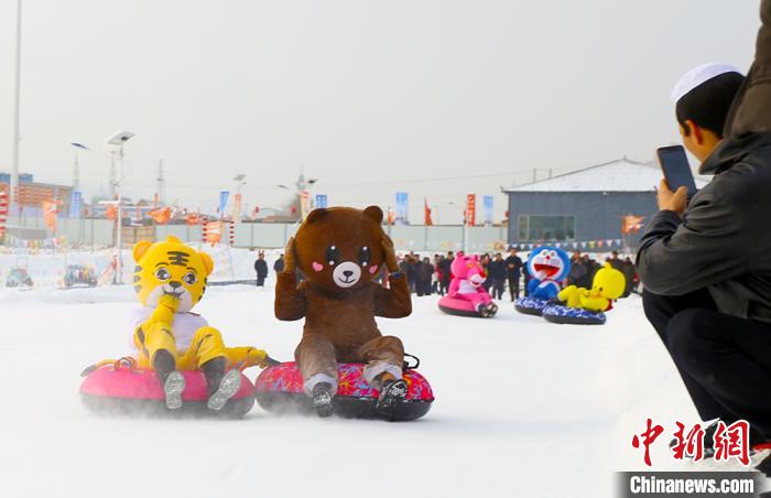 圖為臨夏市南龍鎮(zhèn)馬家莊村舉辦的鄉(xiāng)村文化旅游節(jié)上，游客穿著卡通服裝在體驗(yàn)雪上飛碟項(xiàng)目。近年來，臨夏州形成了“春賞花、夏避暑、秋摘果、冬玩雪”的全季節(jié)旅游產(chǎn)品體系。(資料圖) 高展 攝