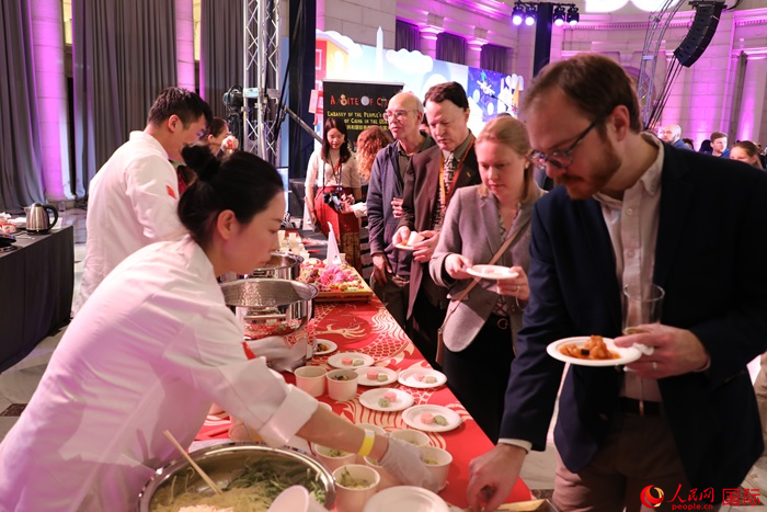 當(dāng)?shù)貢r(shí)間3月7日晚，華盛頓聯(lián)合車站廣場舉行駐美使團(tuán)“使館主廚挑戰(zhàn)賽”。圖為當(dāng)?shù)孛癖娫谥袊古_前體驗(yàn)中國美食。人民網(wǎng)記者 李志偉攝