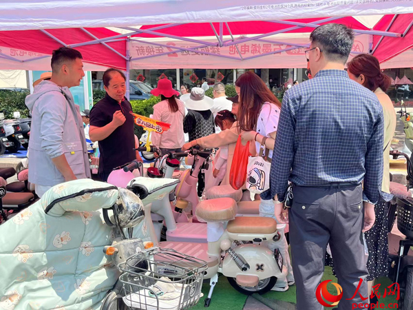 某電動(dòng)自行車品牌工作人員向消費(fèi)者介紹以舊換新相關(guān)情況。人民網(wǎng)記者 杜燕飛攝