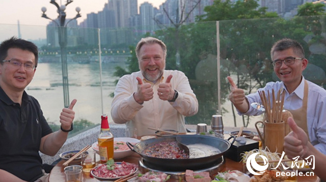 康寧顯示科技事業(yè)部全球拓建項(xiàng)目總監(jiān)軻寶華（中）和同事在重慶南濱路吃火鍋。人民網(wǎng)記者 蘇纓翔攝
