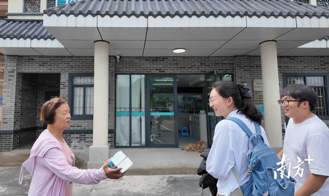 公共服務(wù)組成員王櫻潔（中）和張龍（右）在崖口村衛(wèi)生室前跟村民打招呼。