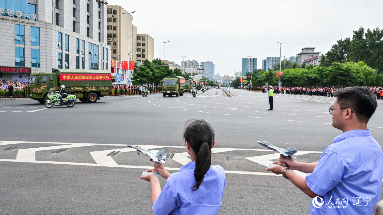航空工業(yè)沈飛的青年技術(shù)人員拿著受閱戰(zhàn)機(jī)的模型迎接烈士遺骸。航空工業(yè)沈飛供圖