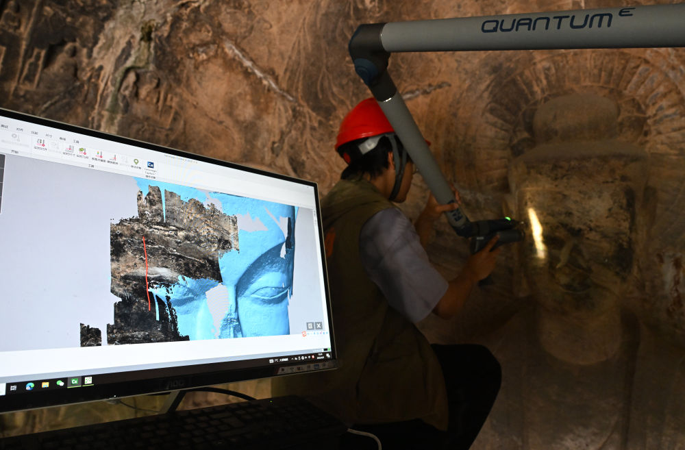 2025年4月9日，武漢大學(xué)文化遺產(chǎn)智能計(jì)算實(shí)驗(yàn)室團(tuán)隊(duì)成員在魏字洞使用關(guān)節(jié)臂掃描儀對(duì)佛像進(jìn)行數(shù)字化掃描。圖片來(lái)源新華社