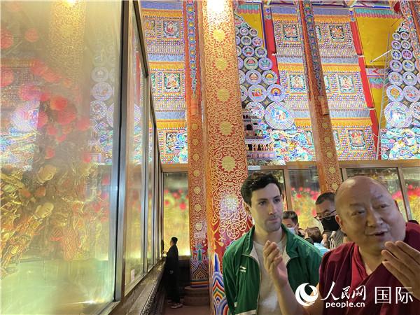 7月25日，省級非物質(zhì)文化遺產(chǎn)項目塔爾寺酥油花的代表性傳承人朋措堅參（右）在塔爾寺酥油花館講解酥油花的制作過程。人民網(wǎng) 謝瑩攝