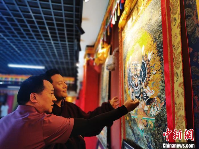 圖為久美尖措展示唐卡作品?！?zhí)砀?攝
