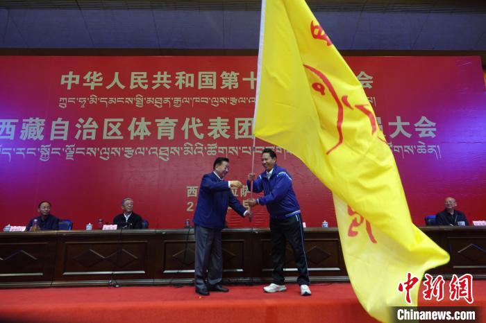 西藏自治區(qū)副主席甲熱·洛桑丹增授代表團(tuán)團(tuán)旗，西藏自治區(qū)體育局局長(zhǎng)尼瑪次仁接旗?！∪轿木?攝