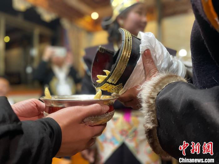 圖為主人在碗中斟滿青稞酒。　冉文娟 攝