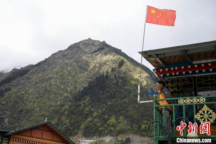 村民站在樓房上觀望?！钊A峰 攝