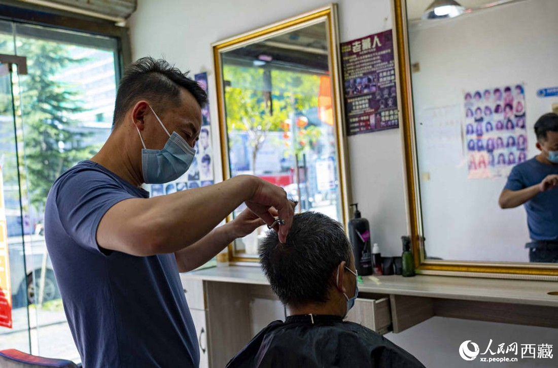 理發(fā)店老板為顧客理發(fā)。次仁羅布 攝