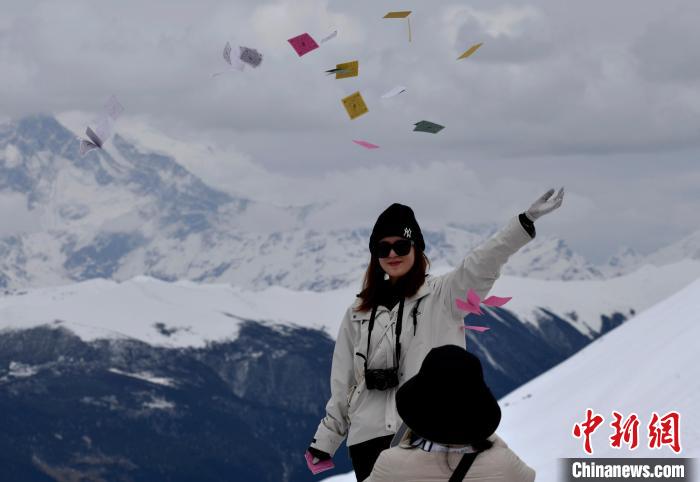 圖為5月14日，游客在西藏林芝色季拉山觀景臺(tái)拋灑“隆達(dá)”(風(fēng)馬旗，藏族民眾的一種祈福方式)。　李林 攝
