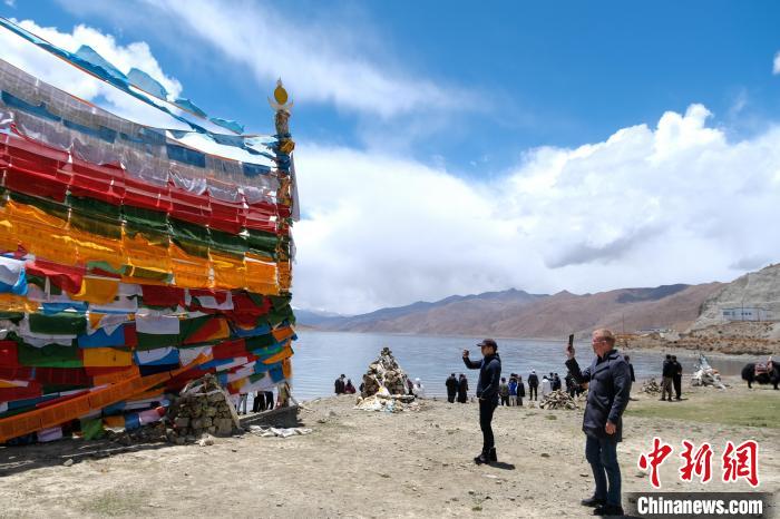 進(jìn)藏參訪嘉賓在羊湖畔拍攝經(jīng)幡。　江飛波 攝