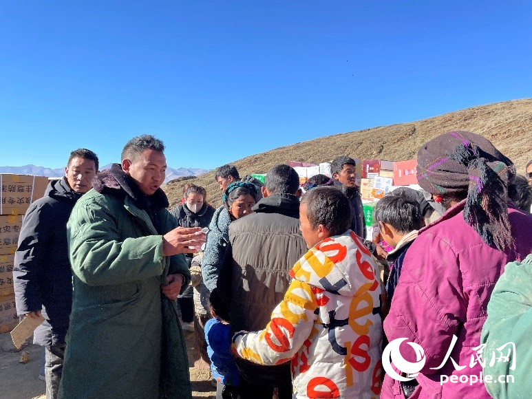 定日縣公安局干警頓珠次仁（左二）正在協(xié)助分發(fā)物資。人民網(wǎng)記者 郝潔攝