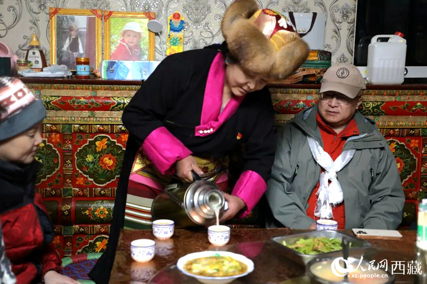 扎西曲登社區(qū)的居民在家中熱情招待遠道而來的游客。居民身著盛裝，為游客倒上熱騰騰的酥油茶，桌上擺放著切瑪與特色美食，賓主共話民族團結(jié)情誼。人民網(wǎng)記者 吳雨仁攝