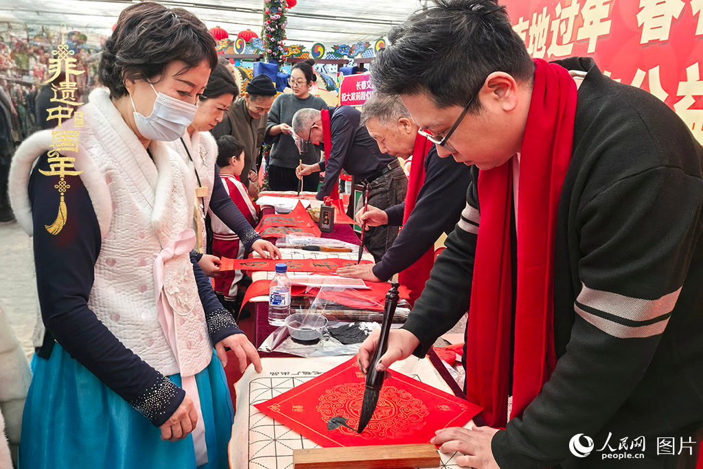 新春佳節(jié)之際，長(zhǎng)春農(nóng)博園冬季展會(huì)火熱進(jìn)行，展廳內(nèi)，書(shū)法家現(xiàn)場(chǎng)書(shū)寫(xiě)“?！弊?，市民游客紛紛上前迎春接“?！薄Ｈ嗣窬W(wǎng)記者 王海躍攝