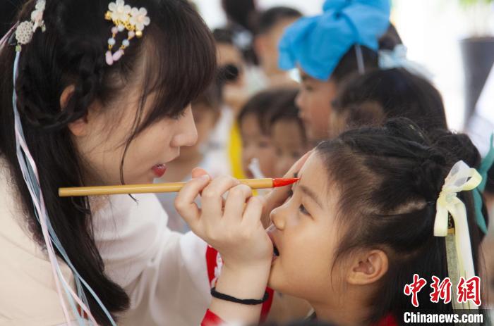 圖為老師在孩子們額頭上點上雄黃，驅(qū)邪辟禍?！《^生 攝